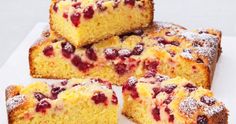 several pieces of cake sitting on top of a cutting board with powdered sugar and cranberry toppings