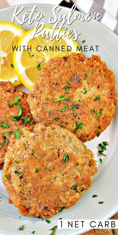 two crab cakes on a plate with lemon wedges