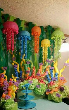 a table topped with vases filled with colorful flowers and jellyfishes hanging from the ceiling