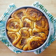 a metal pan filled with pastries on top of a wooden table next to a blue and white towel