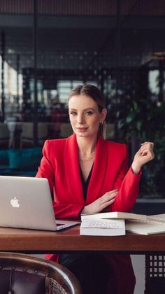 a woman sitting at a table in front of a laptop computer