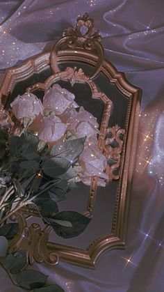 a bouquet of flowers sitting in front of a mirror on a cloth covered tablecloth