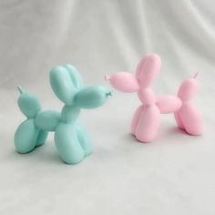 two small balloons shaped like dogs on a white background, one is pink and the other is blue