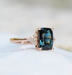 an engagement ring with a large blue stone surrounded by small white diamonds on top of it