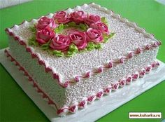 a white cake with pink flowers on it sitting on top of a green tablecloth