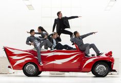 a group of people riding on the back of a red car