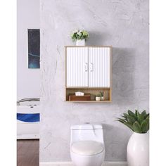 a white toilet sitting in a bathroom next to a wall mounted cabinet and potted plant