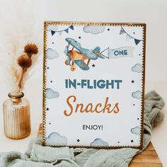 there is a sign that says in - flight snacks on the table next to a potted plant