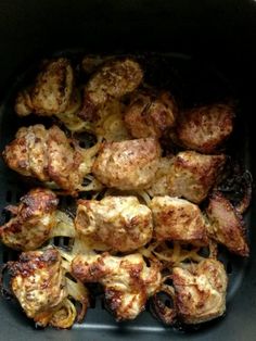 chicken and onions cooking in an air fryer