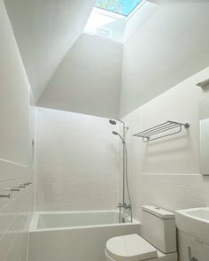 a white bathroom with a skylight above the toilet and bathtub is shown in this image