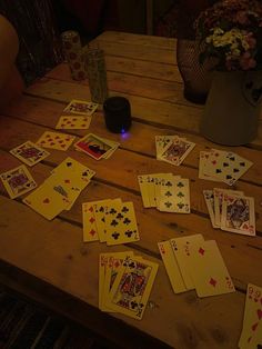 playing cards are scattered on a wooden table next to a vase with flowers in it