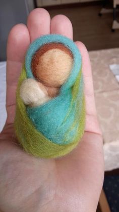 a hand holding a small felted object in it's palm