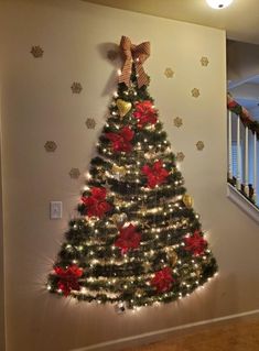 a decorated christmas tree with red and gold ornaments on the top, against a white wall