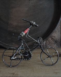 a small metal bike with a red handlebar on it's front wheel and spokes