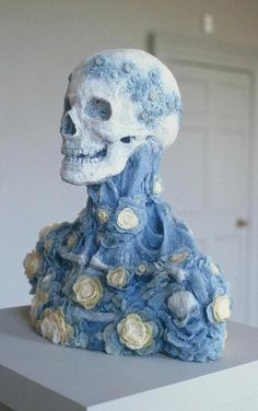 a blue and white skull with flowers on it's head sitting on top of a table