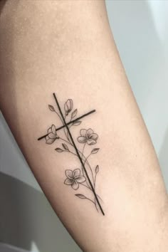 a cross and flowers tattoo on the leg