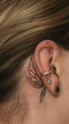 a woman's behind the ear tattoo with wings