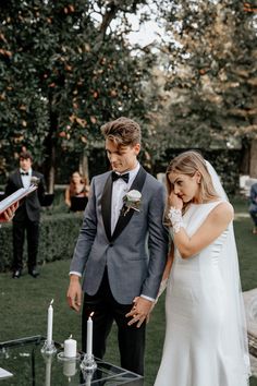 a bride and groom standing next to each other in front of a table with candles