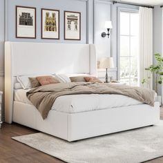 a white bed sitting in a bedroom on top of a hard wood floor next to a window