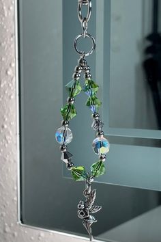 a glass beaded necklace hanging from a hook in front of a door with a mirror behind it