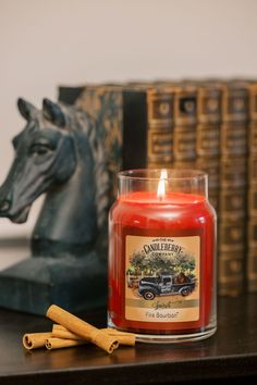 a candle sitting on top of a wooden table next to a horse head and stack of books