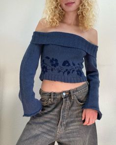 a woman with blonde hair wearing jeans and a blue off the shoulder cropped sweater