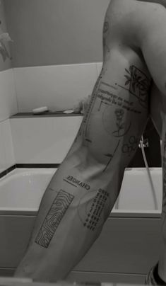 a man with tattoos on his arm standing in front of a sink