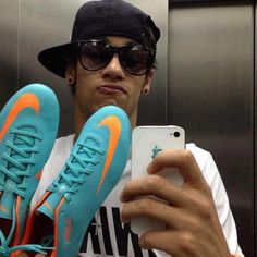 a man taking a selfie in front of an elevator with his blue and orange nike shoes