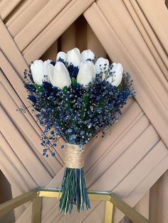 a bouquet of white and blue flowers sitting on top of a table