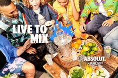 a group of people sitting around a table with fruit and drinks on top of it