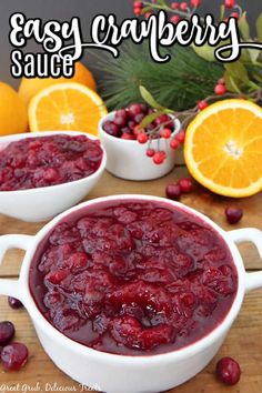 cranberry sauce in two white bowls on a wooden table with oranges and berries