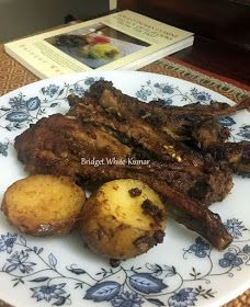 some meat and potatoes are on a blue and white plate next to an open book