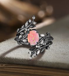 an opal and diamond ring sits on top of a book