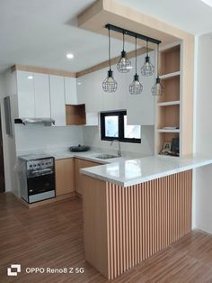 an empty kitchen with wooden floors and white cabinets is pictured in this image, there are hanging lights above the island