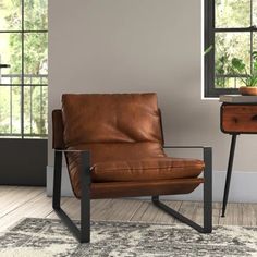 a brown leather chair sitting in front of a window next to a table with a potted plant on it