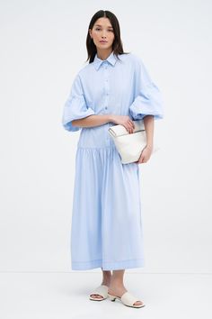 Meet our Ada Dress, the ultimate warm weather staple. She's a midi shirtdress handcrafted from 100% European poplin cotton, featuring pockets and a dropped gathered waistline that falls over your frame with ease. Her clean lines and sharp collar harmonize with dramatic dropped shoulders and full-bodied sleeves, elevating your style for any occasion.[SPLIT] Yada, in light blue, is 5'9" (175 cm) tall, wearing size XS. Shannon, in white, is 5'8" (173 cm) tall, wearing a size M. Maritza, in black an Spring Oversized Cotton Midi Dress, Oversized Cotton Midi Dress For Spring, Cotton Midi Dress With Gathered Sleeves And Relaxed Fit, Relaxed Fit Cotton Midi Dress With Gathered Sleeves, Cotton Maxi Dress With Gathered Sleeves, Cotton Smock Midi Dress, Summer Cotton Smock Midi Dress, Cotton Button-up Maxi Dress For Daywear, Chic Summer Poplin Dress