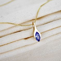 Add a touch of elegance to any outfit with this charming pendant from Ojewellery. Crafted from 9ct yellow gold, this minimalist marquise necklace features a natural tanzanite gemstone in a flush setting. The pendant is branded with the Ojewellery ring logo  and comes with a seller warranty ensuring its quality. The pendant hangs on an 18inch (approx 46cm) curb link chain and fastens with a spring ring closure. It is perfect for any occasion, including Mothers Day, Christmas, weddings, and birthdays. A personalised gift message can be included printed on a card attached to the included gift bag. You will enjoy wearing this necklace and admire the unique blue colour of the main stone. Supplied in an Ojewellery presentation box, within a ribbon handled gift bag, complete with product informat Gemstone Necklace Pendant Unique, Minimalist Pendant Necklace, Marquise Pendant Necklace, Marquise Necklace, Flush Setting, Ring Logo, Tanzanite Pendant, Modern Gold Jewelry, Tanzanite Necklace