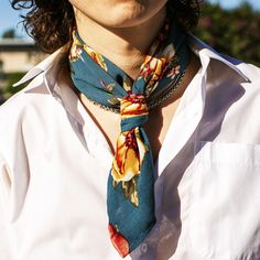 a man wearing a tie with flowers on it is looking off into the distance while standing outside