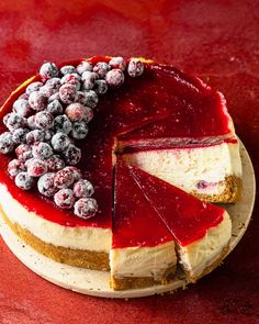 a cheesecake with berries on top sits on a red table