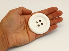 a person's hand is holding a white button