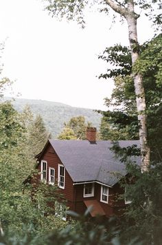 a red house surrounded by trees in the woods