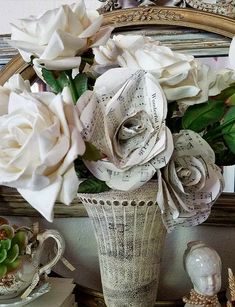 a vase filled with white flowers sitting on top of a table next to a mirror