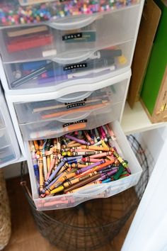 the drawers are filled with different colored pencils and crayons in plastic containers