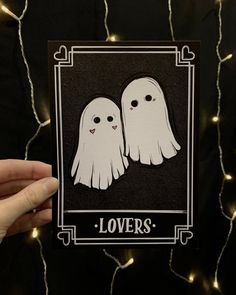 someone holding up a card with two ghost faces on it and the words lover's