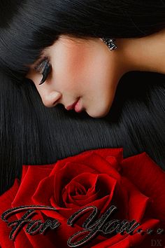 a woman with long black hair laying on top of a red rose and the words for you