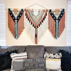 a living room filled with black couches covered in pillows and decorative wall hangings