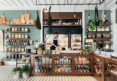 a man standing behind a counter in a store filled with lots of bottles and jars