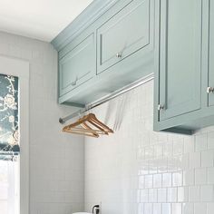 a kitchen with blue cabinets and white counter tops, hanging clothes rails on the wall