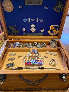 an open wooden box filled with medals and pins