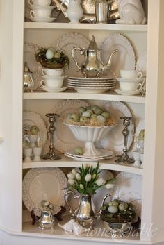 a white china cabinet filled with dishes and cups